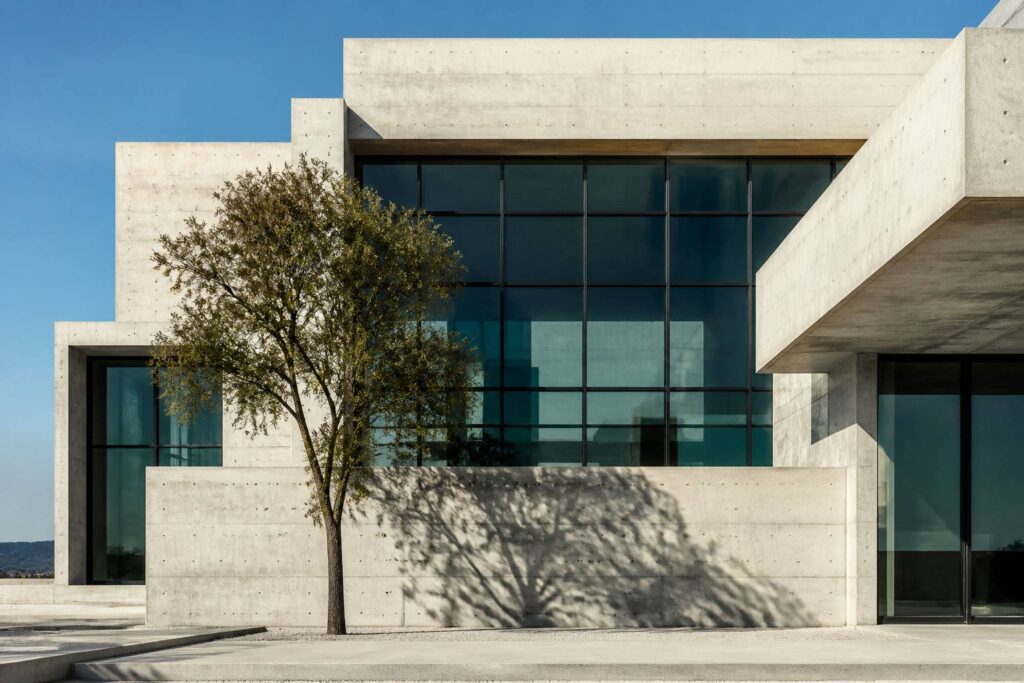 Façade en béton apparent avec baies vitrées et ombres nettes